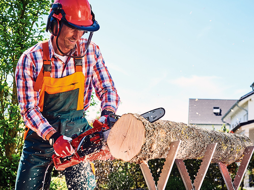 man cuts log with chainsaw