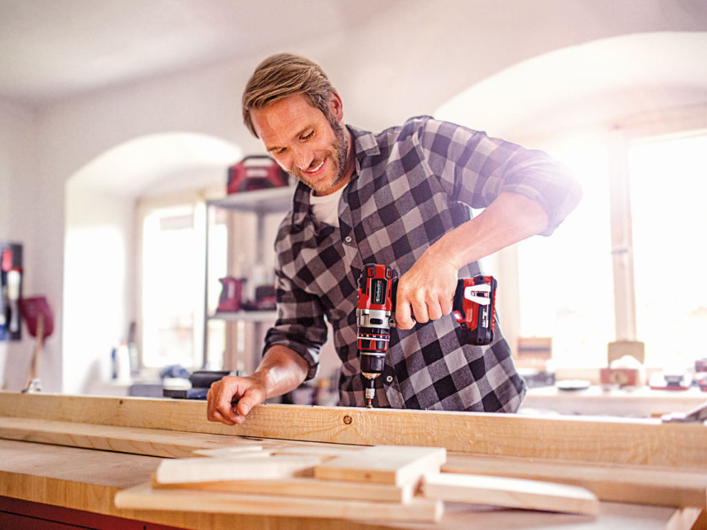 man screws into a wooden beam