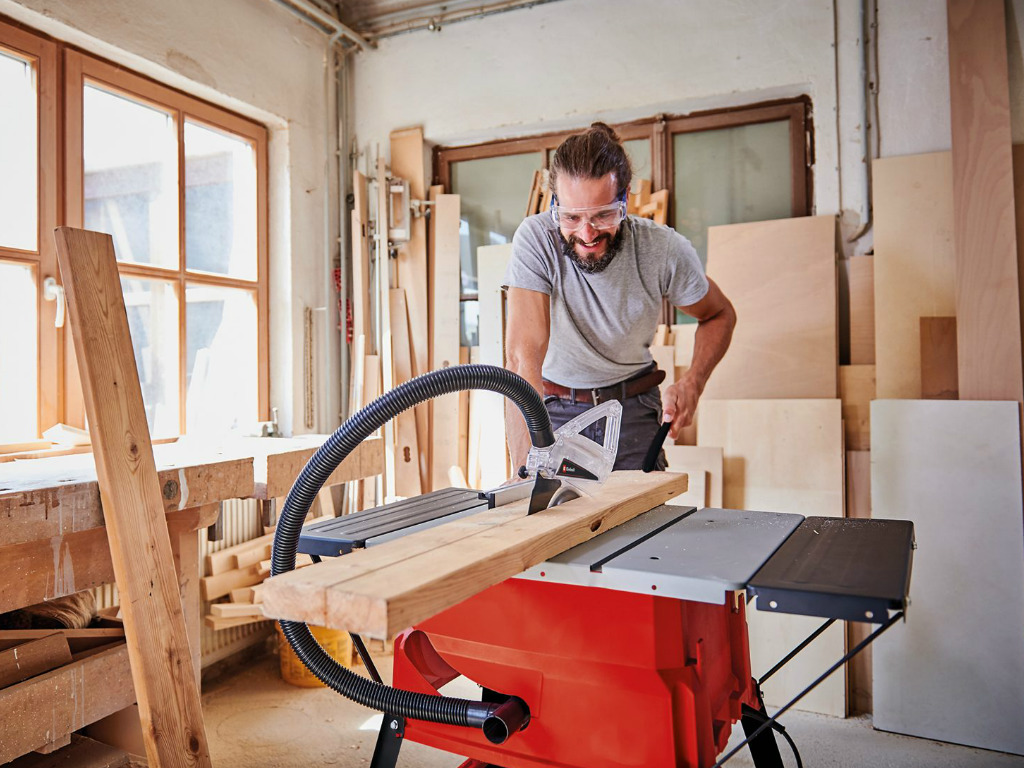 A man cuts a board with a table saw