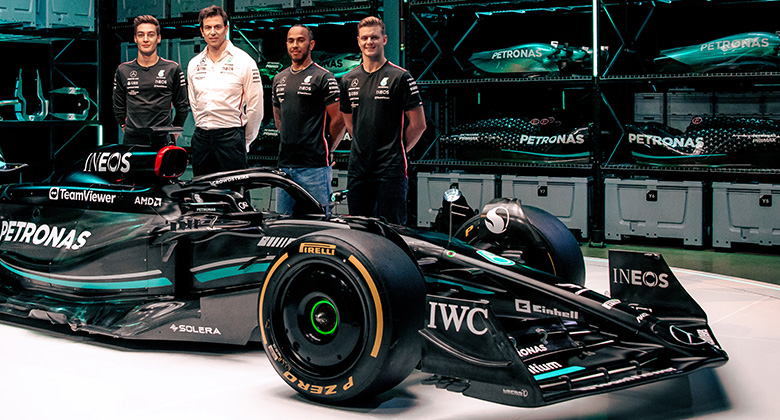 four men stand behind formula 1 car