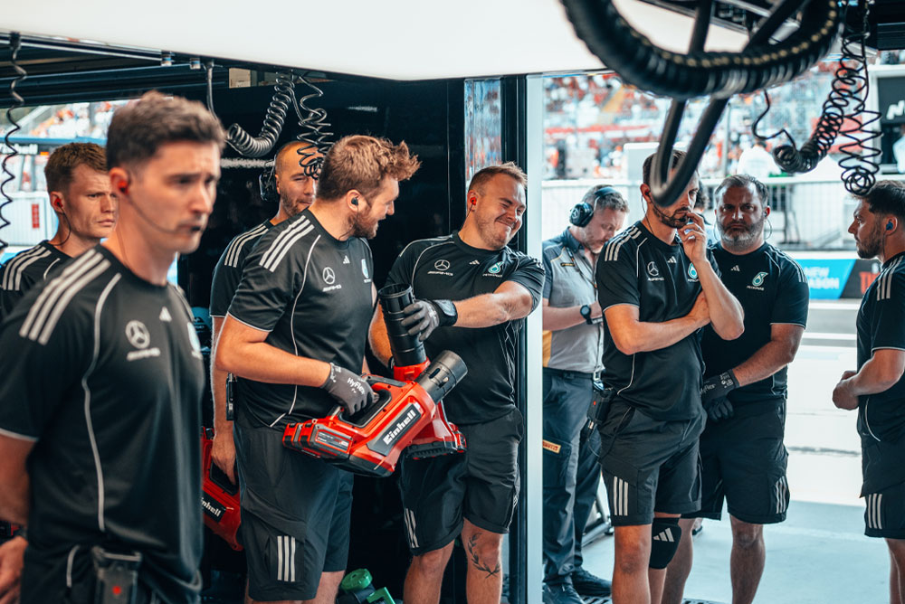 Mercedes-AMG PETRONAS Formula One tim nalazi se u garaži. Dva člana tima drže crvene bežične puhače Einhell i pripremaju se za sljedeću akciju.