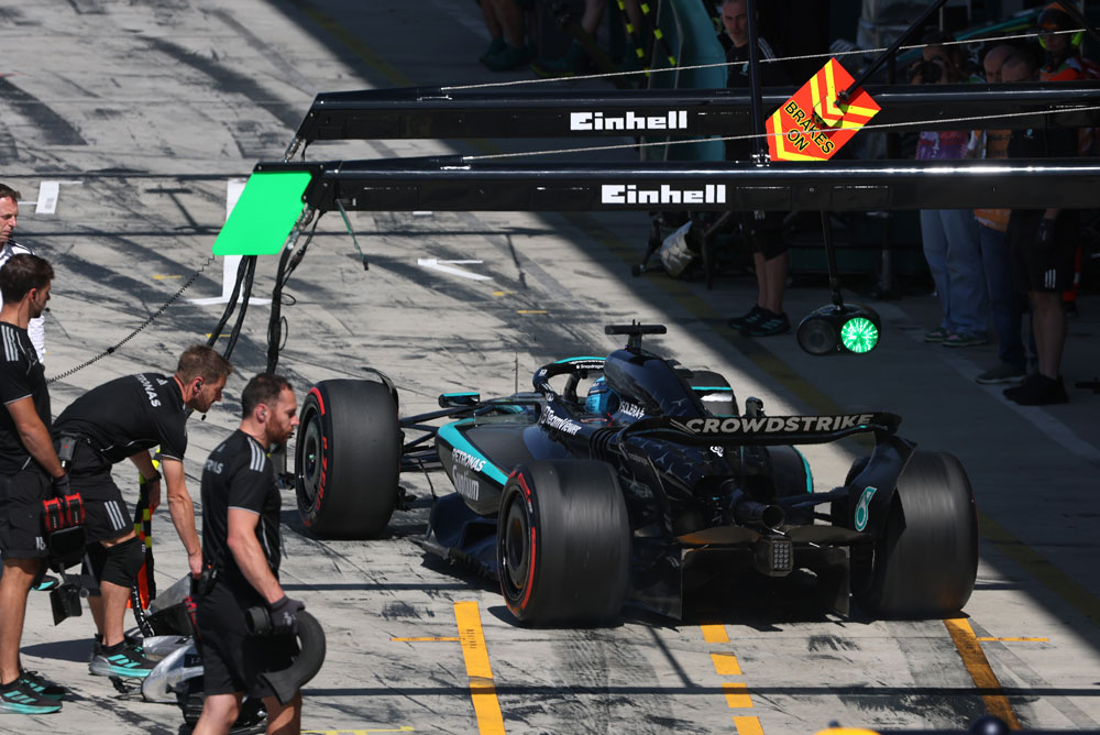 Automobil Mercedes-AMG PETRONAS Formula One tima nalazi se u boksu tijekom zaustavljanja. Nekoliko članova tima stoji oko vozila. Einhell logo vidljiv je iznad područja boksa.