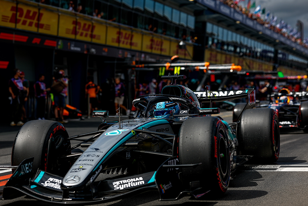 Bolidi Formule 1 u pit laneu okružen timom prije starta.