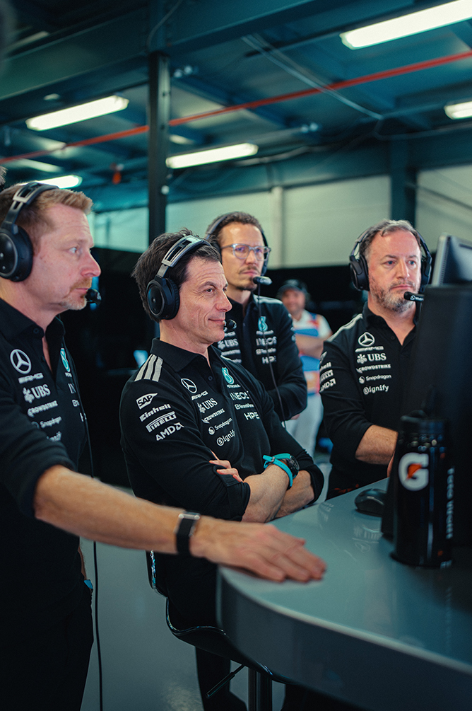 Članovi tima Formule 1 s headsetom prate utrku iz pit zida.