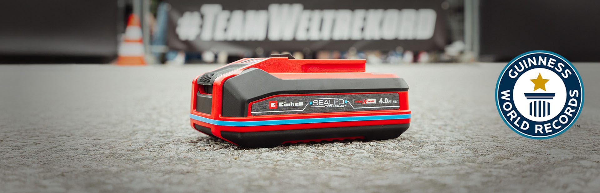Einhell SEALED battery Power X-Change 4.0 Ah lies on asphalt, with the Guinness World Records logo on the right.