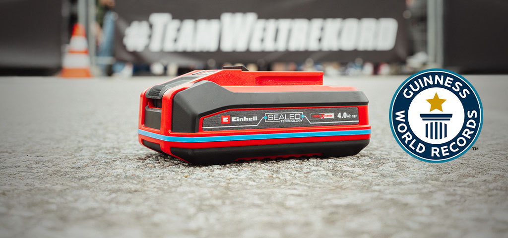 Einhell SEALED battery Power X-Change 4.0 Ah lies on asphalt, with the Guinness World Records logo on the right.