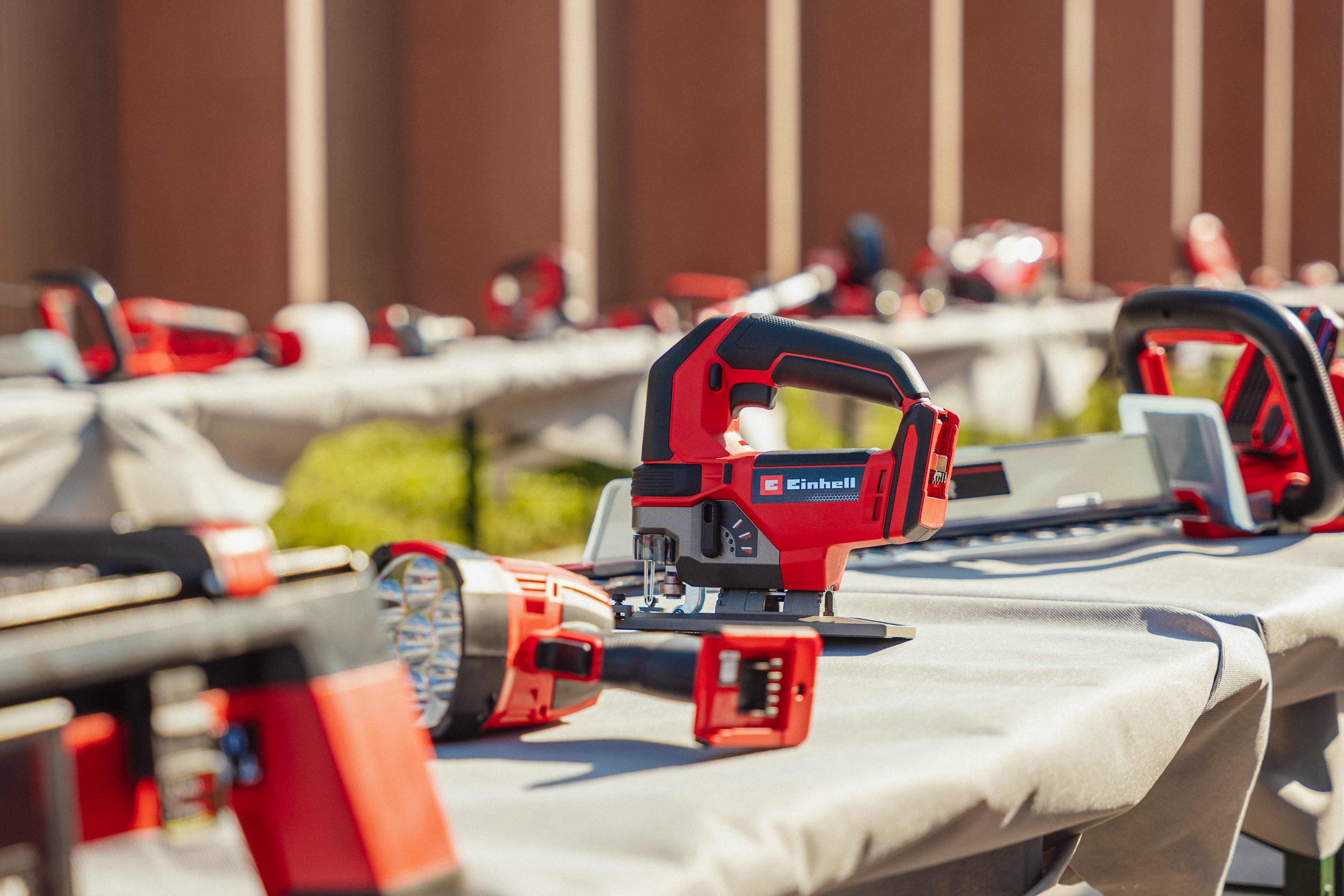 Einhell cordless jigsaw with battery on a table, with an LED cordless lamp in the foreground.