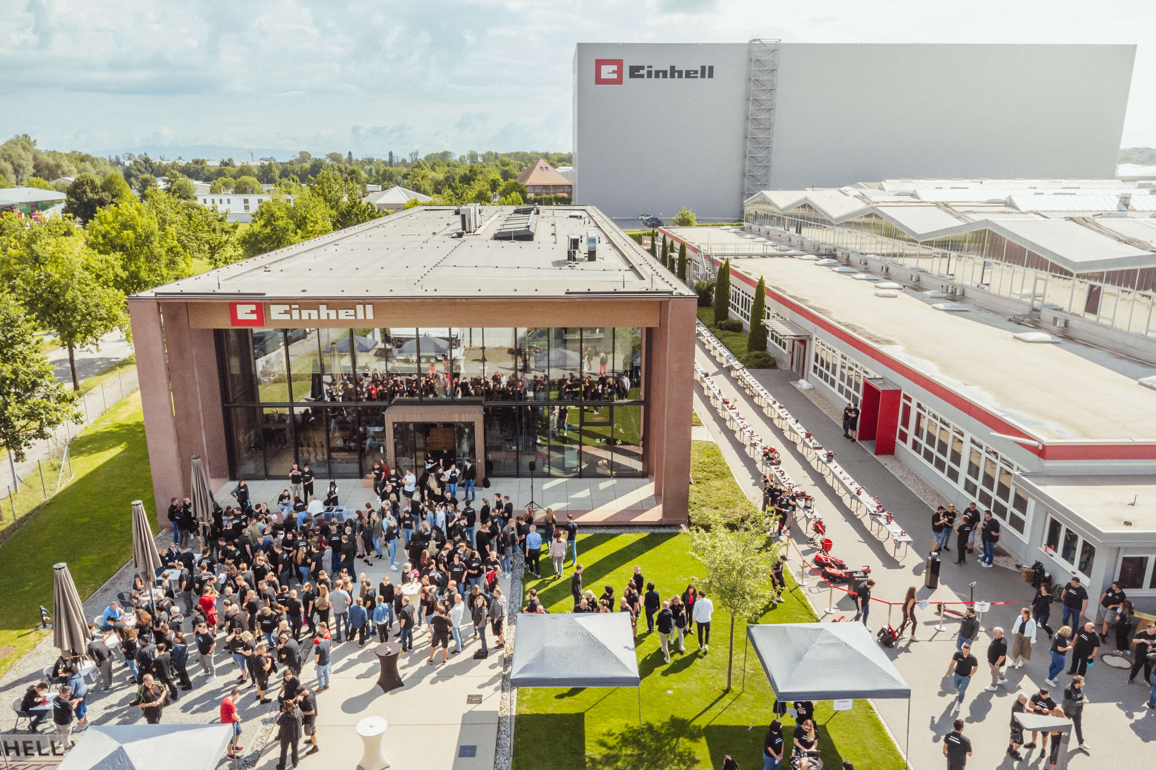 Aerial view of the Einhell company site with many gathered people and set-up tool stations.