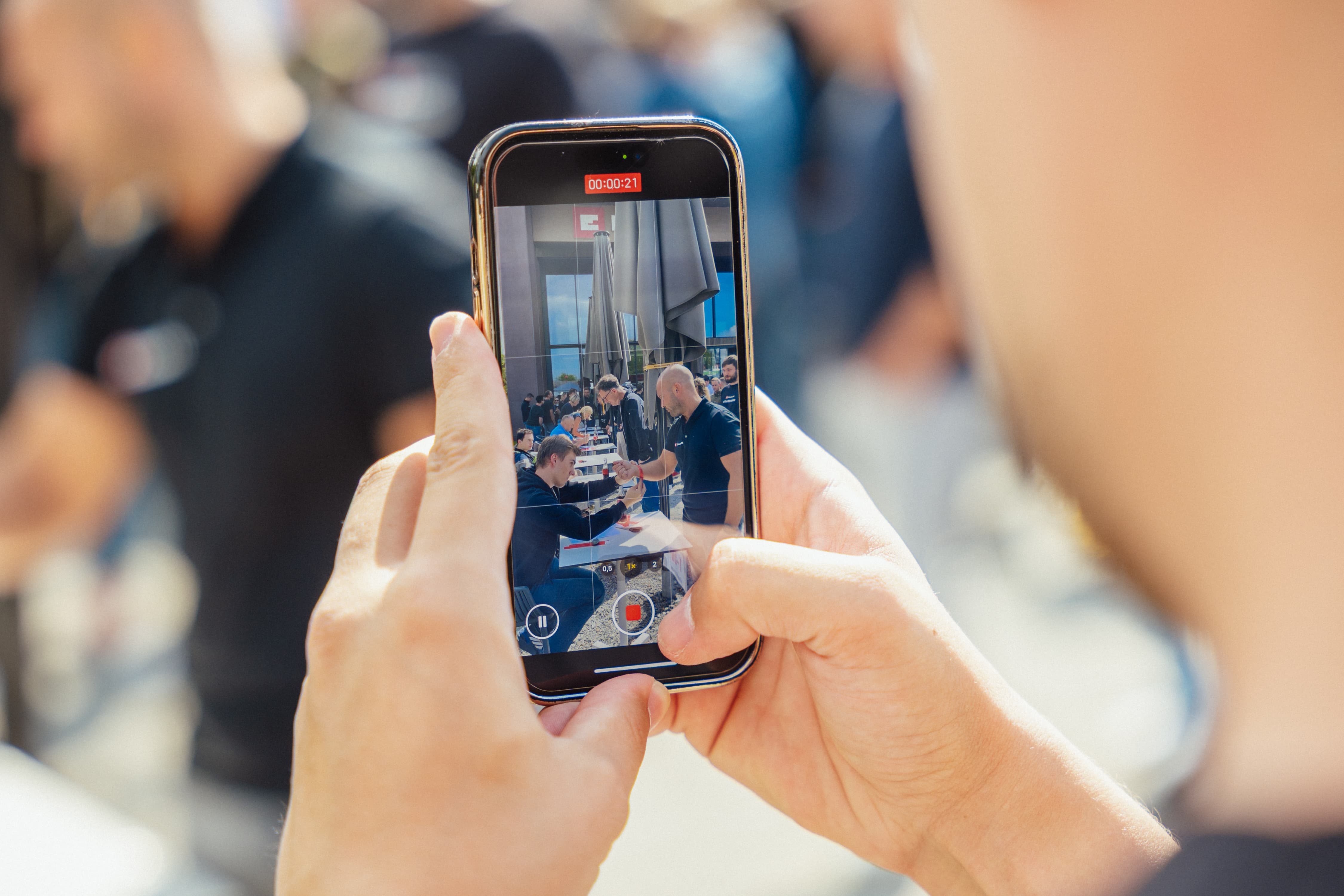 Close-up of a smartphone recording a video of a handshake at the Einhell event.