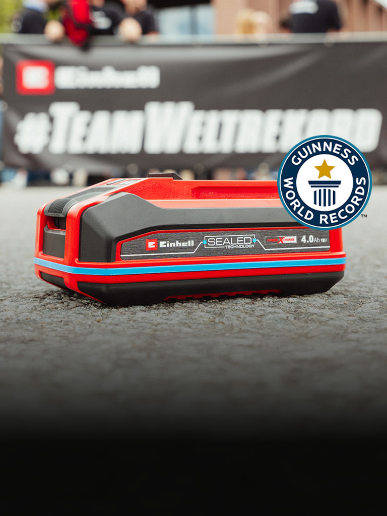 Einhell SEALED baterija Power X-Change 4.0 Ah leži na asfaltu, s Guinness World Records logotipom "Record Holder" s desne strane.