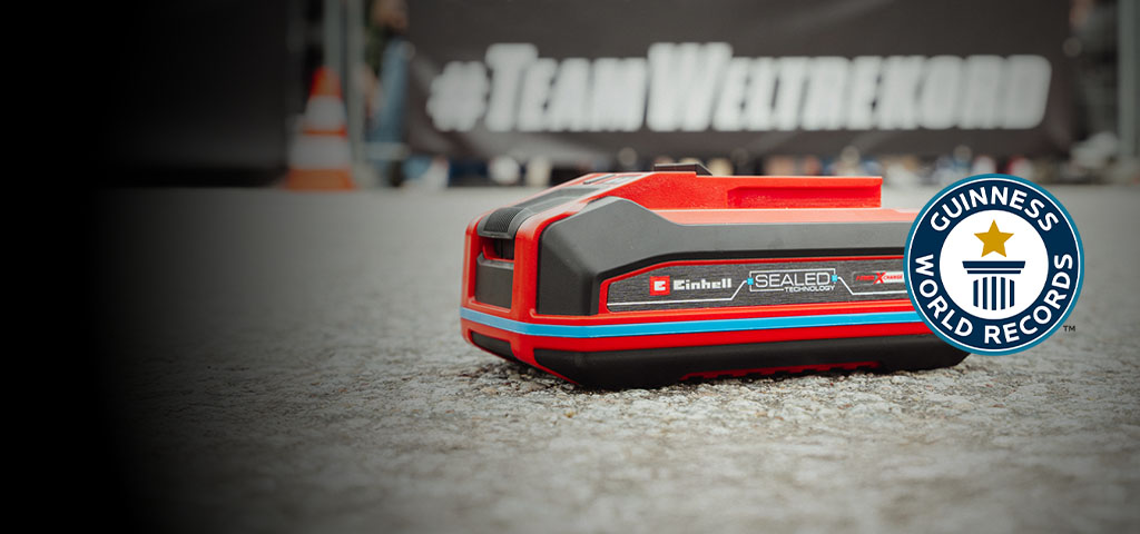 Einhell SEALED baterija Power X-Change 4.0 Ah leži na asfaltu, s Guinness World Records logotipom "Record Holder" s desne strane.