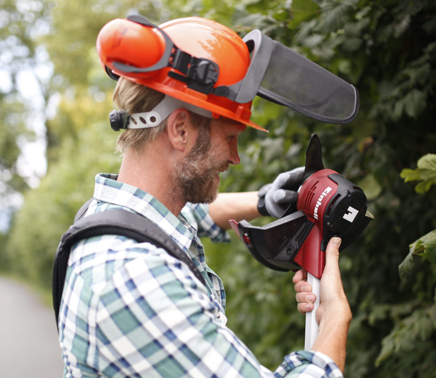 man with a forest safety helmet and a lawn trimmer
