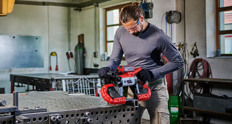 Man sawing metal with a cordless band saw